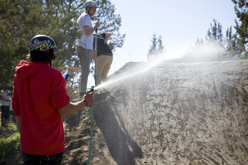 The dirt in Goldman's backyard is a bit sandy so the jumps need constant water and shaping. Lawreny takes his turn and does some watering before the competition begins.