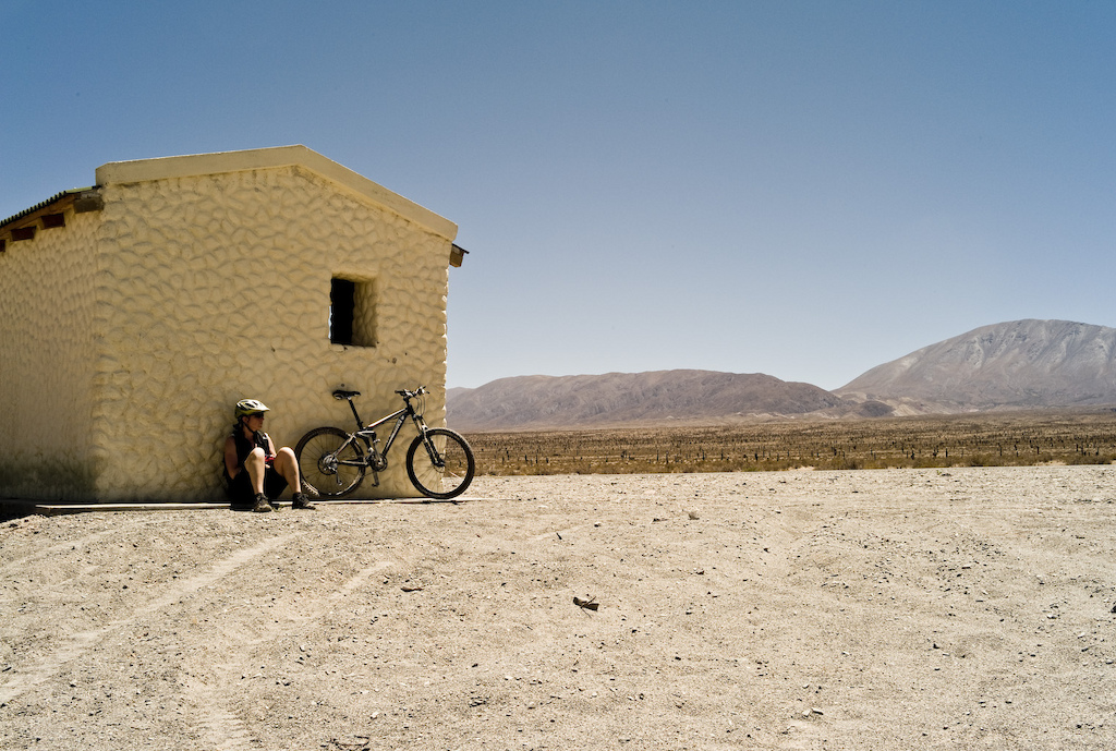 <span style='font-size:12px'>Despite its 2850m/9400 ft altitude, riding in Argentina's Los Cardones Park means getting up early to avoid the midday heat. This desolate cabin was the only shade for miles, providing a short breather.</span><br><br>It's not long before we start to realize that dry riverbeds are about the closest thing we're going to find to bike trails around here and this realization is hammered home at Iruya a remote village tucked away in the mountains up near the Bolivian border. We've heard about hiking possibilities here so assume there will be trails to ride and as we steer our now dusty and clunking rental car over the 4200 meter pass that conceals Iruya from the rest of the world, we scan the vertiginous hillsides for any sign of singletrack. The little village itself is a dash of whitewashed adobe houses glued to the steep valley side. Its streets are cobbled and steep and like everywhere else the tourist office can't relate to our quest to find bike trails. In fact the official is adamant that even the 4x4 track that drops away from the village is unrideable. No-one has bikes here - why would they - as the tracks are rough and the only way out of the village is either back over the 14,000ft pass, by mule along the river bed or up the vertical mountainside opposite. To ride a bike here is downright silliness.
