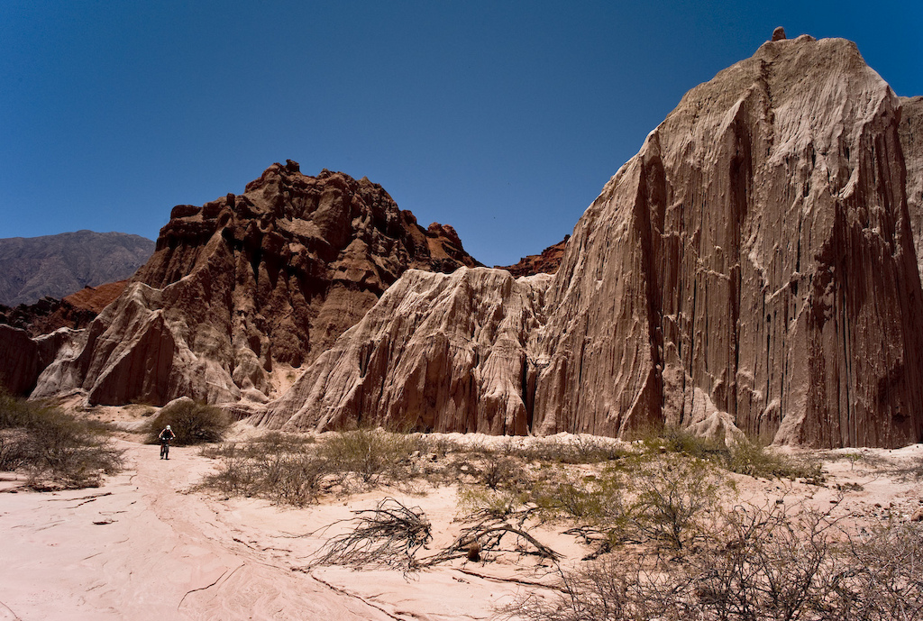 <span style='font-size:12px'>The scenery in the region near El Cafayate is so dramatic that it's hard to take it in, but luckily the dry river beds yielded easy to navigate passages between the thorn bushes allowing us to look up every now and then to appreciate it all.</span><br><br>The town of Cachi has a certain spaghetti western feel to it; dust and horses blow through the main square with equal gusto. It's a charming place though with some damn good local grub to fill up on at night. Devaluation of the Argentine peso although unfortunate for the locals, means that you can eat like a king for less than ten bucks a head. The day's ride ended in Angie's front wheel picking up no less than six thorny punctures making it clear that riding here means keeping a good supply of patches and we wander around Cachi until we find the local bike shop to stock up from. There's a rack of bikes outside the adobe brick house-cum-bike shop and inside a tangle of rusted frames and handlebars are piled high, making it look more like the nest of a giant bike bird than a shop. We learn the Spanish for patches, which is err... 'patches', and ask enthusiastically about trails in the area. From the reply we discern that mountain biking as a recreational pastime has yet to catch on in Cachi. Instead bikes are seen as utilitarian forms of transport, especially viable in this poorer region of Argentina. People here just don't ride bikes for fun.