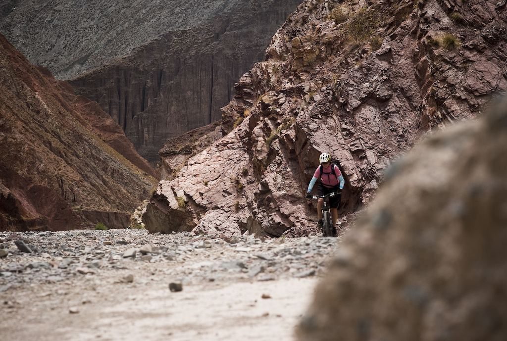 <span style='font-size:12px'>The little village of Iruya sits the -wrong- side of a 4000m pass, meaning a rental car or local bus ride to reach it. Basing ourselves there for a few of days meant being able to explore the trails that spread out from the village hub, all set deep within dramatic scenery.</span><br><br>The problem with vague, hand-scrawled maps of course is that they are sometimes a little too vague and scrawled, hence the cul-de-sac episode. The couple of the trails he has marked in Los Cardones park don't seem to exist, or are perhaps hidden behind a sheen of heat haze. On our return we decide to ride a 4x4 track that snakes invitingly toward some distant canyons. We have learnt the lessons of the previous day's heat and have driven up to the park at 7 am, assembling our bikes (a task at which we become a little too well rehearsed over the next two weeks) in the early rays of soft slanting light while cramming the last morcels of breakfast pastries into our mouths. It's a magical time of the day and is a perfect riding temperature as we steer our bikes into the gentle climb ahead. We are not kidding ourselves that this is sick, singletrack riding or anything similar, but the red and pink landscape that dwarfs us and the feeling of being 'out there' on our bikes is reward enough for now. All around us the hillsides sit like the palette of a sloppy painter, a Jackson Polak masterpiece of shades of red and orange and green. To each side enormous candelabra cacti stand tall and silent like an army of silent but thorny sentries guarding the hills. The climb is an easy gradient, even at 11,000 ft altitude and a cross wind means the soft shells stay on. It's only 15 degrees when we set out. It will be 30 by the time we finish 3 hours later.