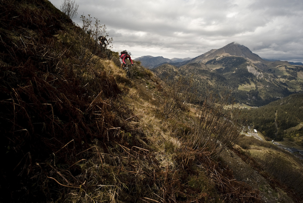 Keith and Mike have a little North Shore-esque play on some picnic benching and then we are off up a short, sharp grunt that brings us out above Les Crozets. In summer we'd ride the DH track down to the lift but this time we find a traversing singletrack that is fast and loose and cut across way above the empty DH trails. Fast jeep track encourages a race down to the bottom before we start the 200 metre uphill. The sun has had chance to dry things out and traction is back and welcome. The climb that looked foreboding from the other side of valley turns out to be 99% ride-able (100% with a little steely commitment and the lungs of a whale) and as we near the Col de Cou we're almost disappointed that it's ending. The views from the top are compensation enough and our disappointment soon fades as it dawns on us that it's all downhill from here back to Morzine.